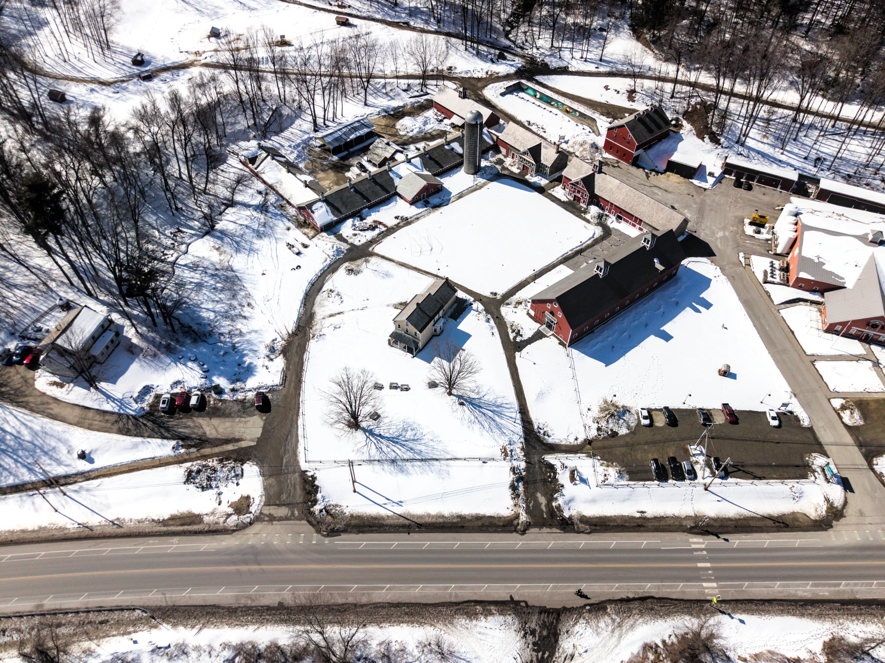 Aerial view of farm buildings and a silo surrounded by snow